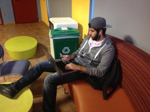 Student sits in cafeteria working on his laptop.