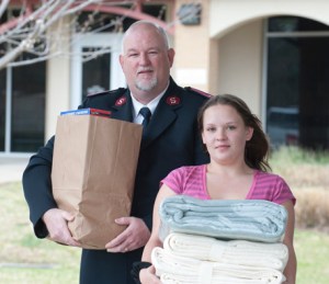 Photo illustration of male volunteer holding bag of donations and girl volunteer holding blankets