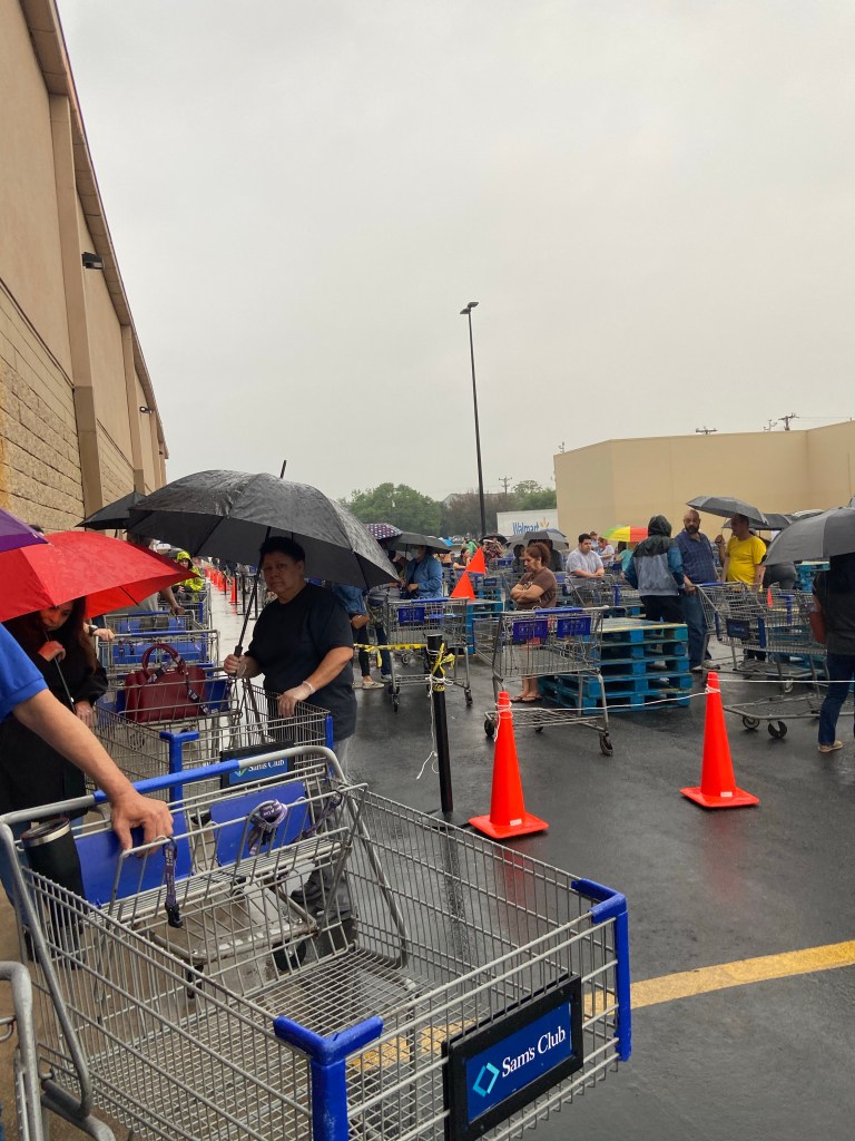 Photo of customers waiting in rain to enter Sam’s.